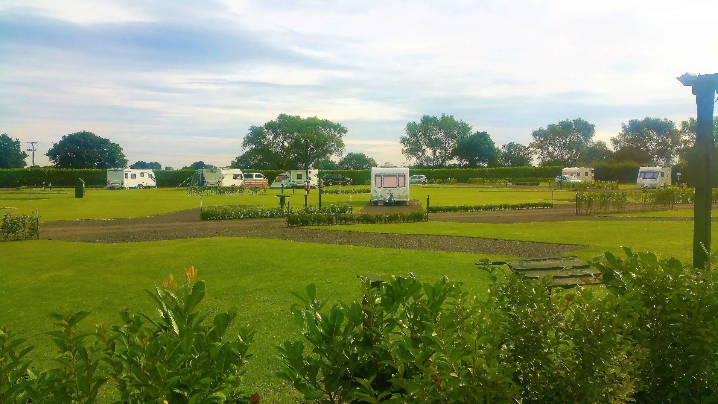 Open grassed field with caravans in the distance