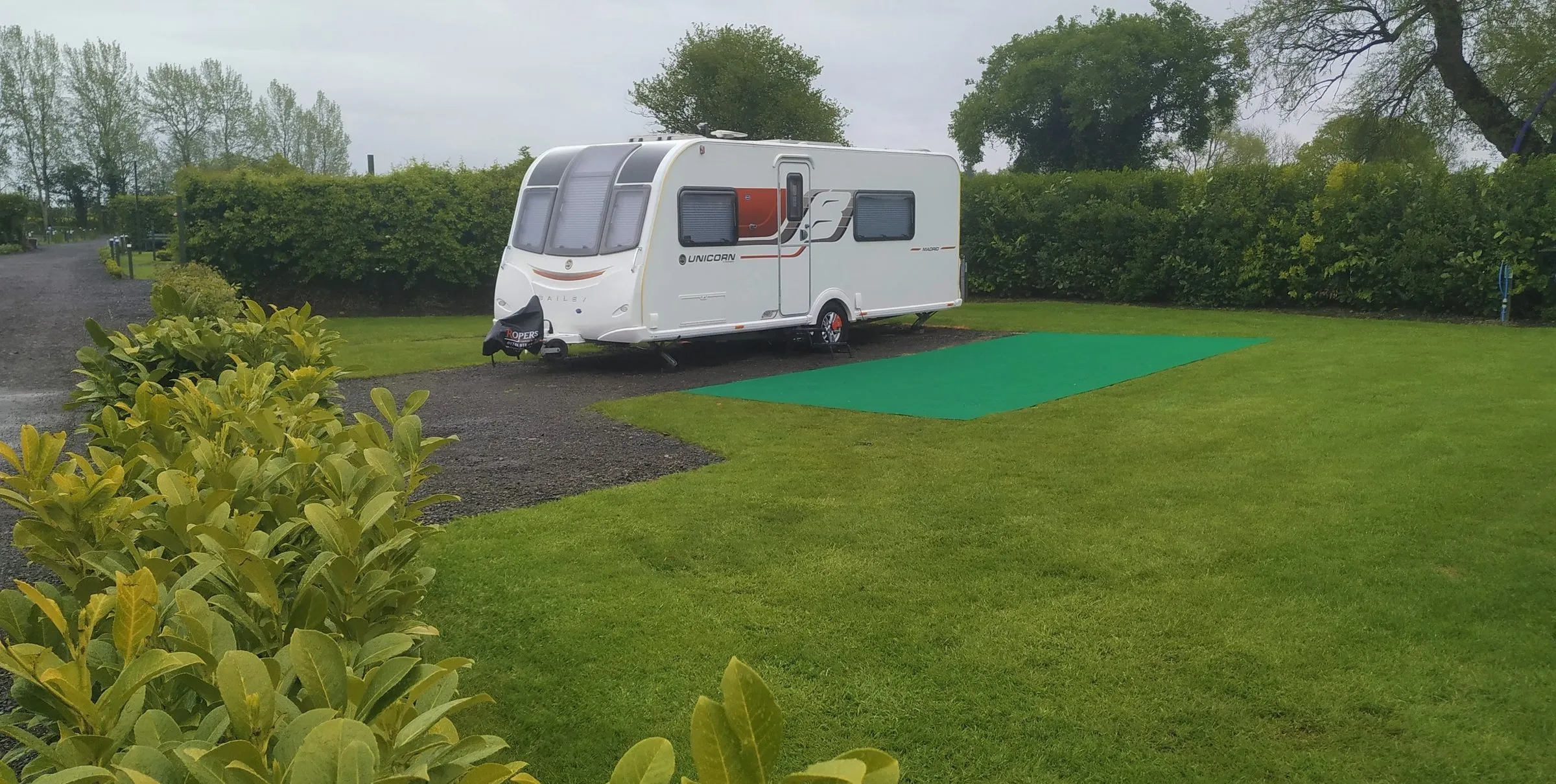 A caravan on its hard-standing pitch with a grassed garden area